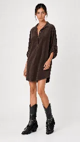 Vestido corto de estilo camisero con silueta amplia y fluida. Presenta cuello camisero, cierre frontal parcial con botones, mangas largas con detalle de ajuste y bolsillos laterales.