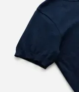 Remera azul marino de viscosa con cuello redondo y mangas cortas. Presenta un bordado con motivos marineros en el frente. Corte regular.