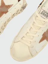 Zapatillas Golden Goose modelo Super Star, de diseño desgastado, con estrella lateral en gamuza marrón y detalle de animal print en el talón.