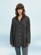 Camisa oversize de denim color gris oscuro, con cierre frontal de botones metálicos, cuello camisero, mangas largas y un bolsillo aplicado en el pecho.