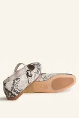 Zapatos tipo Mary Jane con estampado de piel de serpiente, capellada de cuero vacuno, forro y plantilla de cuero vacuno, y suela de cuero. Tienen un taco bajo de 1 cm y una correa con hebilla negra sobre el empeine.