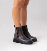 Bota corta tipo chelsea de cuero vacuno color marrón, con suela track de goma negra y elástico lateral.