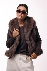 Chaleco acolchado color marrón con terminaciones de piel sintética en los bordes y cuello, aportando volumen y textura.