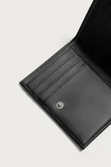 Billetera vertical de cuero sintético negro con cierre de botón a presión, ranuras para tarjetas y compartimento con cierre lateral para monedas.