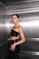 Top corto negro de charol con escote recto y espalda con cierre desmontable central.