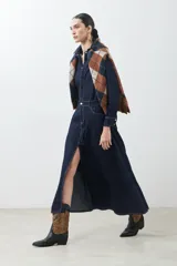 Vestido camisero de jean azul oscuro, corte evasé, largo midi, con cuello camisero, cierre frontal con botones, mangas largas con puños abotonados, bolsillos en el pecho y tajo lateral.