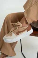 Zapatillas bajas color beige y marrón, con cordones y suela blanca.