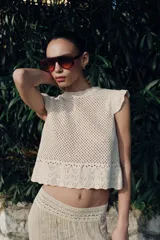 Top de cuello redondo y mangas sisa con volantes, confeccionado en tejido de punto calado con algodón y bajo con detalle de volantes.