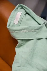 Camisa de manga larga color verde menta con cuello camisero, bordado con la frase "mon amour" en la solapa del cuello, cierre frontal con botones y bolsillo ojal en el pecho. Marca Bartola.