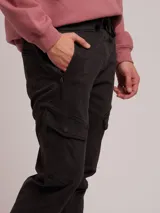 Pantalon cargo de sarga color negro, con cintura elástica ajustable mediante cordón, bolsillos laterales tipo cargo y puños elásticos en los tobillos.