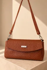 Cartera de cuero vacuno color marrón chocolate, con textura entrelazada y solapa frontal que incluye placa metálica con la marca "PECARÍ". Cuenta con correa de hombro ajustable y desmontable unida mediante mosquetones metálicos.
