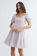 Vestido corto de algodón con estampado de cuadros vichy en color lila y blanco, escote corazón, mangas cortas abullonadas y falda escalonada con volantes.