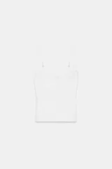 Top corsetero blanco de escote redondo con tirantes finos ajustables. Presenta detalles de frunces en el pecho y costuras verticales marcadas.