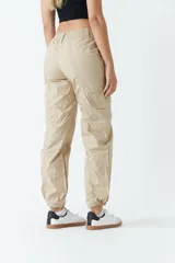 Pantalón cargo color beige de tiro medio, con bolsillos laterales tipo cargo y puños ajustables en los tobillos.