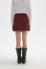 Falda mini de gamuza sintética color bordó, con diseño cruzado y cierre de botón frontal.