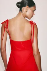 Vestido midi negro con cuello halter y falda acampanada con volumen.