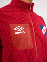 Buzo de micropolar azul con medio cierre frontal, cuello alto y bolsillo con cierre en el pecho. Presenta el logo de Umbro y el escudo del Club Nacional de Football.