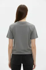 Remera de algodón negra de manga corta y cuello redondo, con estampa frontal que incluye letras rojas y gráficos en tonos dorados.