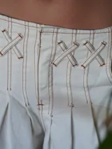 Pantalón wide leg de tiro medio confeccionado en denim, con cintura trabajada con pasacintas entrelazadas, cierre frontal y bolsillos laterales.