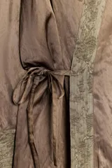 Kimono de la colección ZW de Zara, confeccionado en tejido marrón con acabado satinado. Presenta solapas anchas en tono verde con estampado estilo jacquard y flecos largos colgantes en el frente. Cuenta con mangas largas con puños estampados y bolsillos laterales ocultos.