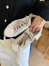 Championes urbanos de mujer con diseño de malla texturizada en color negro y detalle metálico en tono dorado en el talón. Poseen una suela gruesa y resistente, ideal para uso diario.