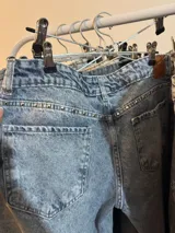 Jean de tiro bajo con corte wide leg y diseño de cinco bolsillos. Presenta un lavado clásico en tono azul medio con efecto desgastado.