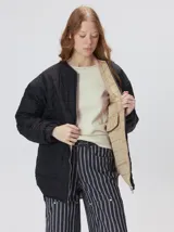 Campera reversible capitoneada con cierre frontal. Un lado es de color negro y el otro es de color beige, ambos con diseño acolchado. Cuenta con cuello redondo, mangas largas y bolsillos laterales.