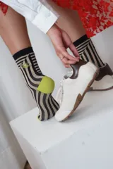 Medias de caña media con estampado de líneas onduladas en tonos beige y negro, talones y punteras en color verde lima y detalle de bordado en el lateral.