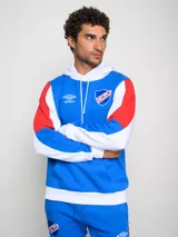 Canguro de felpa Umbro del Club Nacional de Football, con diseño tricolor en rojo, azul y blanco. Presenta capucha con cordones ajustables, bolsillo tipo canguro frontal, logo de la marca y escudo del club bordados en el pecho.