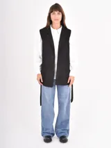 Chaleco largo de color negro con solapas clásicas y bolsillos frontales, diseñado con un corte recto y abierto.