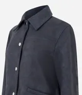 Chaqueta de corte recto confeccionada en suede sintético color marrón. Presenta cuello estilo camisa, cierre frontal con botones metálicos, mangas largas con puños ajustados y bolsillos embutidos.