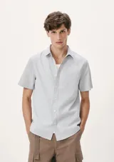 Camisa celeste con estampado de microcuadros, de manga corta, con cuello clásico y bolsillo en el pecho.