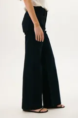 Pantalón de jean azul oscuro, de corte acampanado, con bolsillos delanteros y traseros, y costuras verticales en el frente.