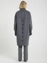 Chaqueta larga de paño color gris, con cuello y puños acanalados, cierre frontal con botones y bolsillos laterales.