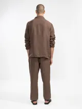 Chaqueta verde oliva de lino italiano, corte relajado, con tres bolsillos frontales y cierre con botones.