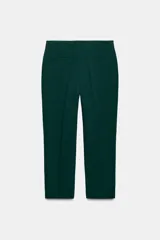 Pantalón de tiro alto color beige, de corte recto y largo tobillero, con bolsillos laterales y cierre frontal con cremallera y ganchos metálicos.
