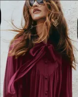 Blusa color borgoña con cuello alto con lazo, mangas 3/4 abullonadas y peplum.