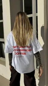 Remerón negro de algodón con estampado frontal en letras blancas con la frase “On my way to buy overpriced coffee”.