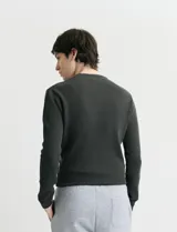 Sweater de punto con textura waffle, color negro, de corte clásico con cuello redondo y mangas largas con puños ajustados.