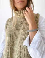Chaleco tejido a mano color beige con cuello alto y sisas amplias.