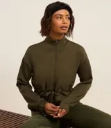 Campera deportiva color verde militar, confeccionada en modal. Tiene cuello alto, cierre por cremallera y lazo para ajustar en la cintura.