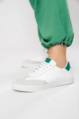 Zapatillas acordonadas de cuero color blanco con puntera de gamuza gris y detalles en verde.
