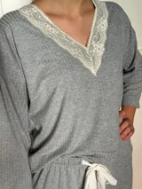 Pijama de algodón gris con textura acanalada, compuesto por una remera de escote en V decorado con puntilla y un pantalón recto con elástico y lazo en la cintura.