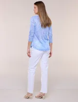 Blusa celeste con estampado floral devoré, de manga tres cuartos, escote redondo amplio y detalle de pechera de encaje blanco en contraste.