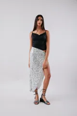 Falda midi plateada de lentejuelas, con tajo lateral y nudo en la cintura.