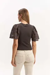 Remera color tostado con cuerpo acanalado y mangas cortas abullonadas con bordados calados.