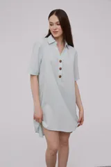 Vestido corto tipo túnica color celeste, de lino, con cuello camisero, mangas cortas y cierre frontal con botones de madera.