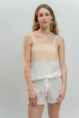 Pijama de dos piezas confeccionado en algodón, compuesto por una musculosa de escote recto con detalle de puntilla elastizada en color durazno y un short haciendo juego con elástico y lazo en la cintura.