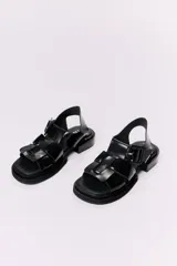 Sandalias negras de cuero charol con plataforma y taco bajo. Presentan tiras anchas con hebilla cuadrada grande en el empeine y tira de sujeción en el talón.