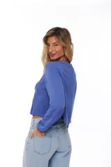 Blusa azul con escote en V y lazos, mangas largas y detalles bordados en el pecho.
